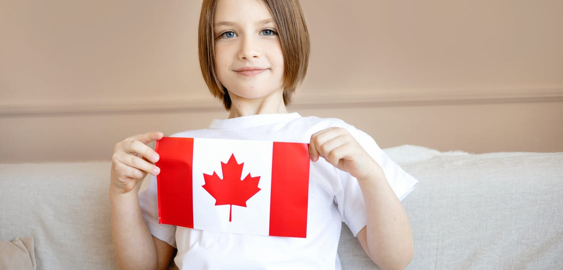 A kid holding the Canadian Flag