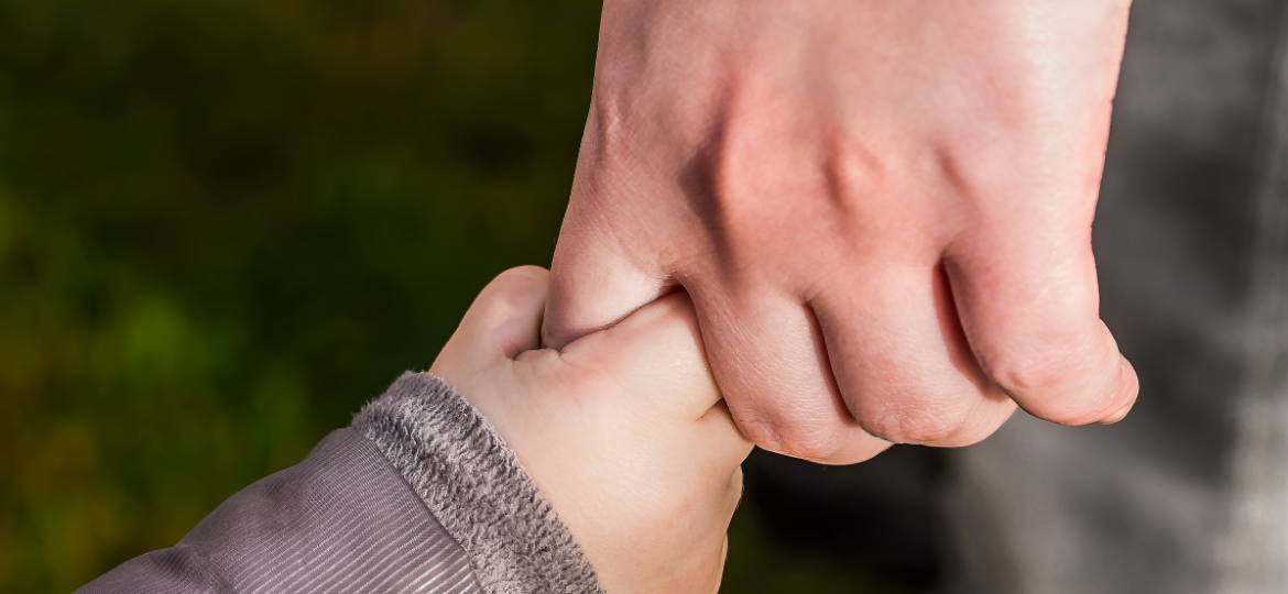 A person holding the hand of a child