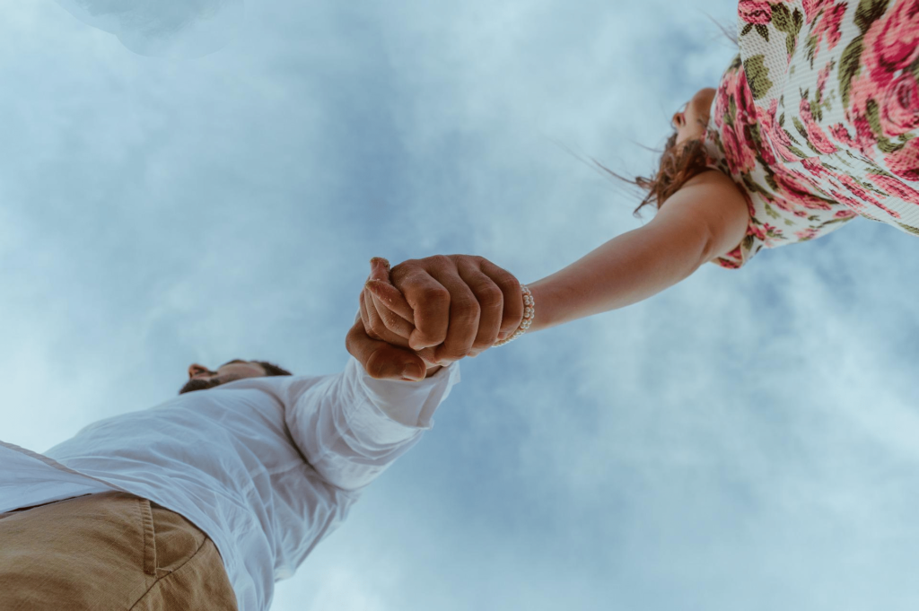Couple holding hands against a cloudy sky