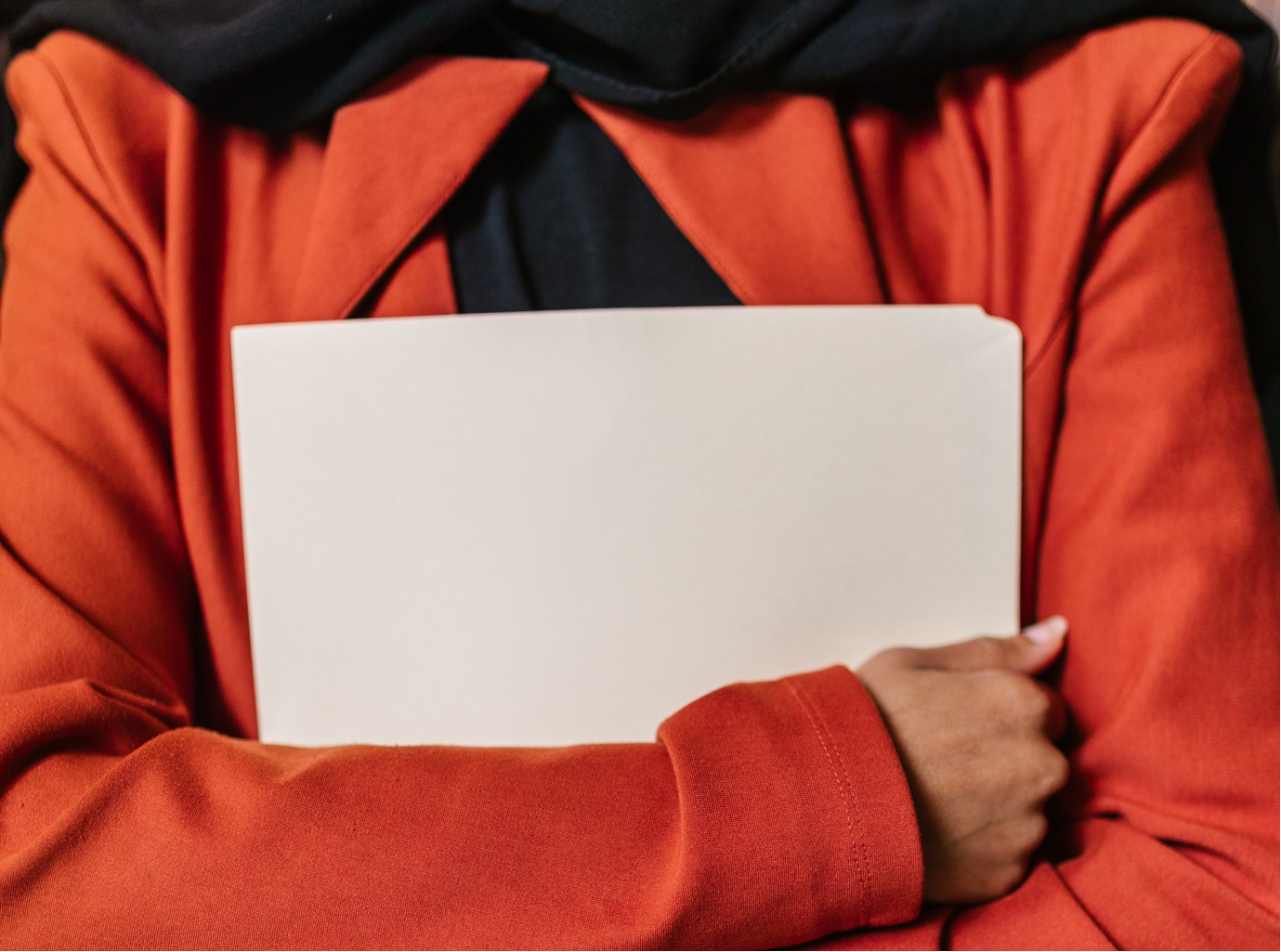 Woman in orange blazer holding white folder