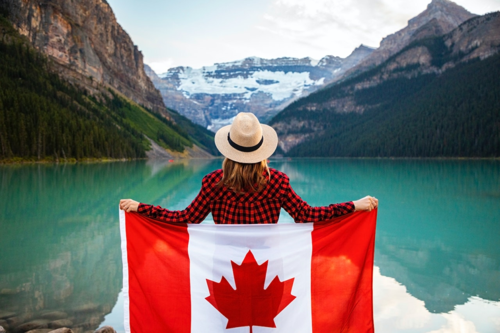 A person holding the Canadian flag near a body of water