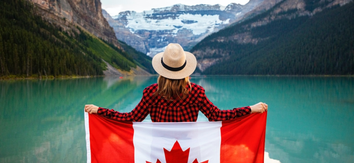 A person holding the Canadian flag near a body of water
