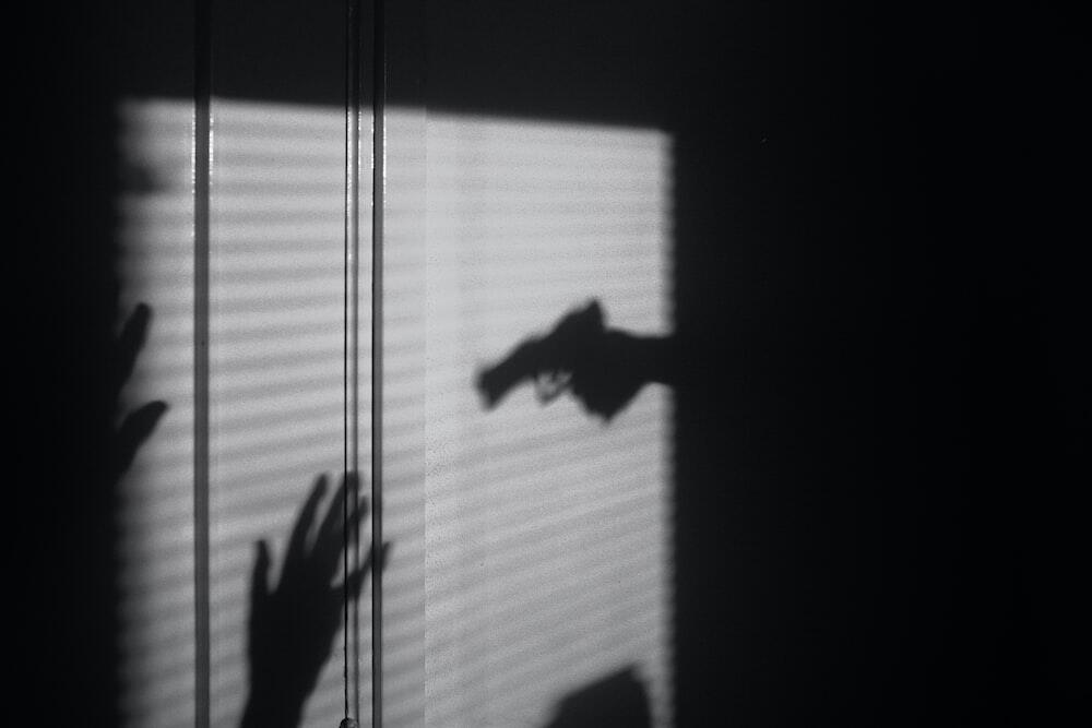 Shadow of a person pointing a gun towards a victim