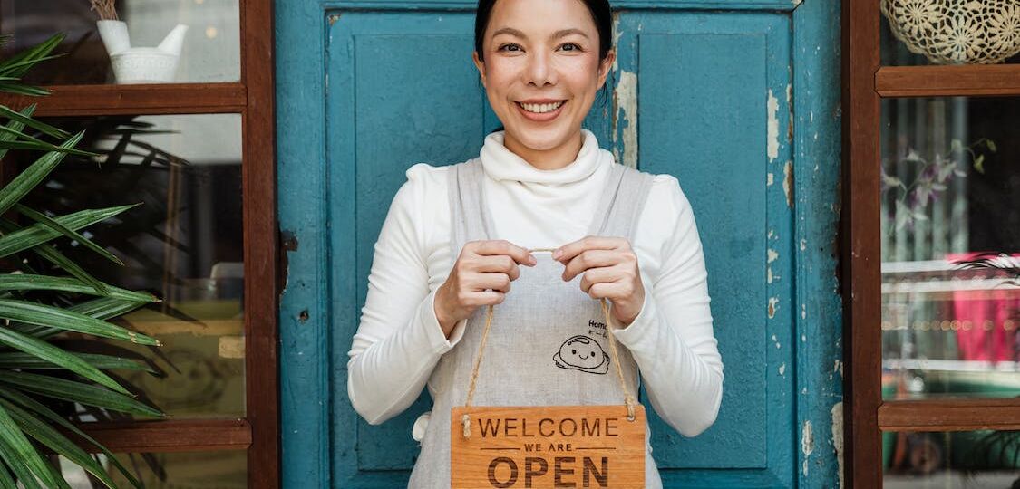small business owner holding an open sign for her business