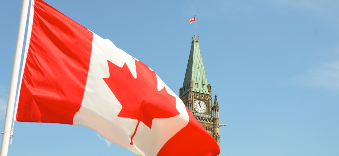 Canada’s flag in front of a clock tower.