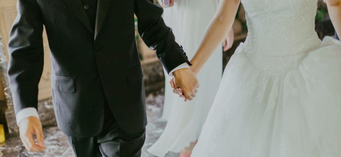 An image of a couple holding hands at their wedding