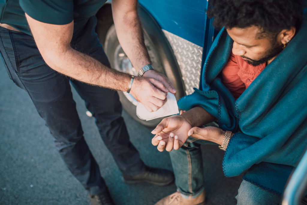 An image of a man putting a bandage on another man’s hand